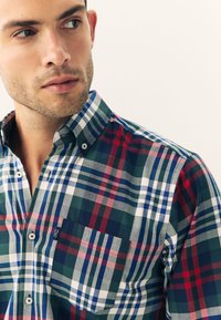 Chemise boutonnée avec un motif à carreaux multicolores comprenant des nuances de vert, rouge, bleu et blanc ; dotée d'un col et d'une poche poitrine.