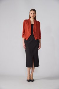 Red cropped blazer with a shawl collar over a black fitted dress featuring a front slit. Worn with black high-heeled shoes.