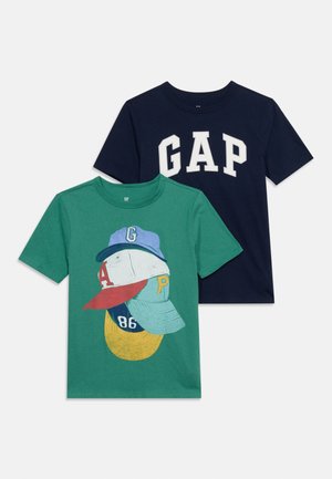 Two folded short-sleeve kids' T-shirts; one navy with white "GAP" text, one green with colorful caps and numbers graphic on front.