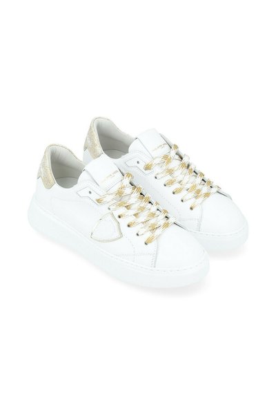 Baskets en cuir blanc avec des détails dorés, présentant une texture lisse, une semelle blanche épaisse et des lacets à motif doré.