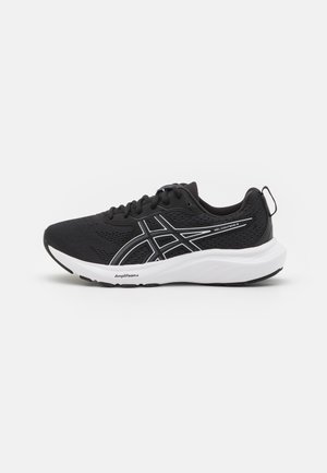 Zapatilla deportiva negra con suela blanca, rayas blancas con el logo en el lateral y cordones, mostrada desde el lado exterior sobre fondo blanco.