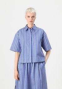 Camicia a maniche corte a righe blu e bianche con colletto, caratterizzata da una vestibilità ampia e un orlo dritto.
