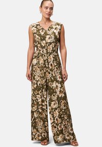 Combinaison florale en vert olive, avec un décolleté en V, des manches courtes, une taille élastique et un design à jambes larges orné de fleurs beiges et d'accents noirs.