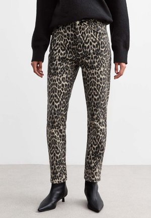 Jeans de estampado de leopardo en beige y negro, diseño ajustado, cintura de altura media, con detalles desgastados, combinados con botas negras hasta el tobillo.