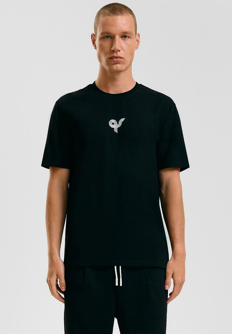 Zwarte katoenen t-shirt met korte mouwen, voorzien van een grijs logo op de linkerborst. Het ontwerp is eenvoudig met een ronde hals.