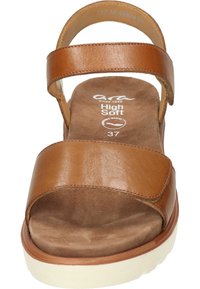 Sandal de cuero marrón con dos correas anchas, plantilla acolchada, punta redondeada y suela blanca texturizada para estabilidad y comodidad.