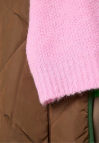 Kootud roosa sviiterisvärk, ribaga mansetiga, kihina peal pruunist tikitud kangast, millel on diagonaalsed õmblused ja roheline aktsent.