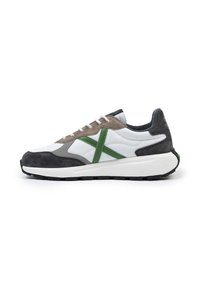 Zapatillas que presentan una combinación de cuero blanco, gamuza gris y acentos verdes. Punta redondeada, suela blanca gruesa y paneles texturizados en contraste.