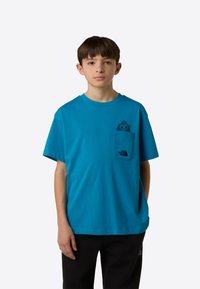 Turkizno bombažna majica z okroglim izrezom, kratkimi rokavi, sprednjim žepom z risanim dizajnom in majhnim logotipom na dnu žepa.