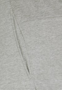 Lichtgrijze sweatshirtstof met een zachte, gestructureerde oppervlakte, featuring een opvallende kangoeroezak en ribbeldetails langs de randen.