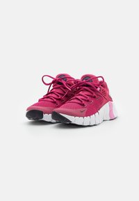 Rosa atletiske sko med en åndbar mesh-overdel, rund tå og struktureret hvid sål. Har snørebånd og en diskret logo-detalje.