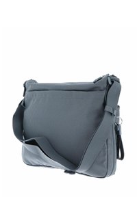 Sac messager gris en tissu texturé, présentant une fermeture éclair, une bandoulière réglable et un profil mince avec un motif à pois subtil.
