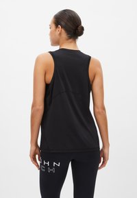 Svart ärmlös sporttopp med en texturerad bakpanel, som har en avslappnad passform och en nederkant som täcker midjan.