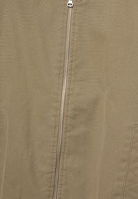 Giacca khaki con zip, caratterizzata da una cerniera in metallo argentato, texture liscia e dettagli con motivo trapuntato sul lato sinistro.