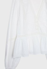 Weiße Bluse aus leichtem Stoff, ausgestattet mit einem tiefen V-Ausschnitt, Knopfverschluss und aufwendiger Stickerei, mit einem ausgestellten Saum und Puffärmeln.