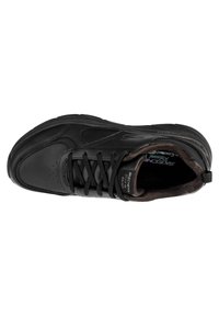 Scarpa atletica nera con tomaia in pelle liscia, punta arrotondata e design con lacci; presenta logo e soletta testurizzata, con suola ammortizzata.
