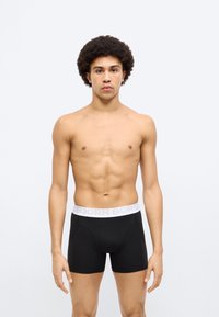 Μαύρα ανδρικά μπόξερ με λευκή μέση που φέρει την ετικέτα «BJORN BORG». Το υλικό φαίνεται λείο και ελαστικό, με εφαρμογή που αγκαλιάζει το σώμα και ενισχυμένες ραφές.