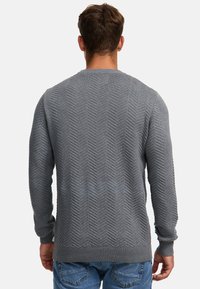 Pulover tricotat gri cu un model în zigzag, guler rotund și manșete și tiv elastic. Materialul pare moale, cu o finisare texturată.