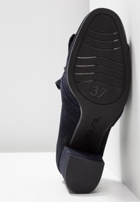 Chaussure à talons hauts en suede navy avec une semelle en caoutchouc texturée. Taille 37 marquée sur la semelle, dotée d'un large talon pour la stabilité.