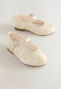 Ballerinas in Creme mit strukturiertem Blumenmuster, verstellbarem Riemen und einer dekorativen silberfarbenen Schnalle an der Seite, flache Gummisohle.