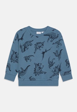 Sweat-shirt pour tout-petit à manches longues bleu avec des illustrations noires de dinosaures, comprenant des motifs de Tricératops, Stégosaurus et Ptéranodon.