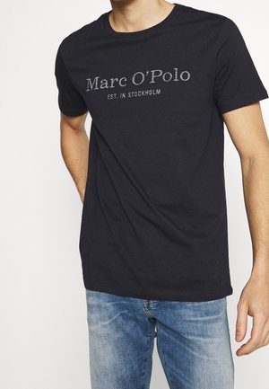 Schwarzes Baumwoll-T-Shirt mit Rundhalsausschnitt, das ein graues, bedrucktes Logo "Marc O'Polo EST. IN STOCKHOLM" über der Brust zeigt. Lässige Passform.