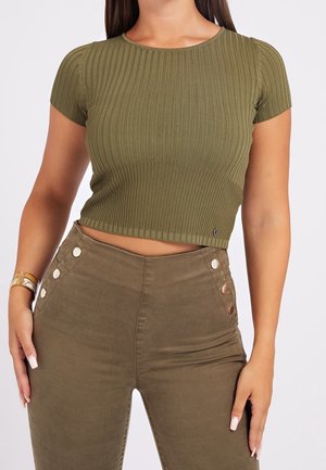 Olivengrøn ribstrikket crop top med korte ærmer, kombineret med højtaljede olivengrønne bukser med dekorative knapper i siden.