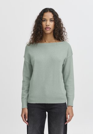 Light green sweater with a wide neckline, long sleeves, ribbed cuffs, and hem. Slightly loose fit, made from soft, textured fabric.