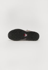 Semelle en caoutchouc noir avec un motif texturé, dotée d'un accent triangulaire rose. La partie supérieure est de couleur claire, semblant durable et légère.