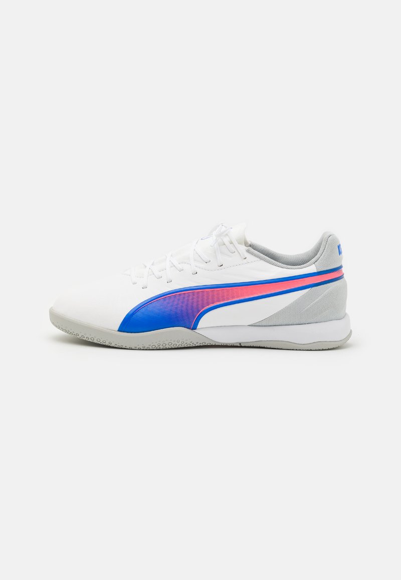 Zapatillas deportivas blancas con una parte superior lisa, que presentan una franja de acento en azul y rosa, puntera redondeada y suela texturizada en gris.