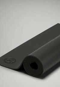 Černá jóga podložka stočená, vyrobená z texturovaného materiálu, s logem na okraji, s hladkým povrchem a zaoblenými konci.