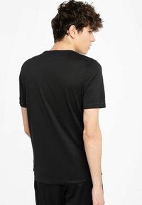 Sort kortærmet t-shirt lavet af glat stof, med rund halsudskæring, let tætsiddende design og en ensfarvet ryg uden mønstre.