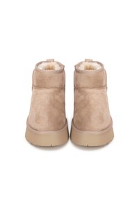 Botas de tobillo de ante color canela con un suave forro de piel sintética y una suela de goma. Presentan una puntera redondeada y detalles de costura en los laterales.