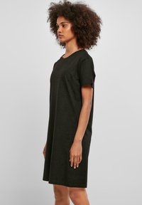 Rochie tricou din bumbac negru, cu mâneci scurte, guler rotund și croială lejeră, care ajunge puțin deasupra genunchiului. Textură moale, fără modele.