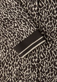 Cardigan en maille à imprimé léopard beige et marron foncé, présentant des motifs beige clair, une fermeture à boutons et un col côtelé avec des accents rayés.