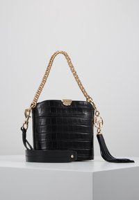 Borsa a secchiello in pelle nera con motivo a coccodrillo, manico a catena dorata, hardware con logo, tracolla removibile e accentuazione con nappina nera.