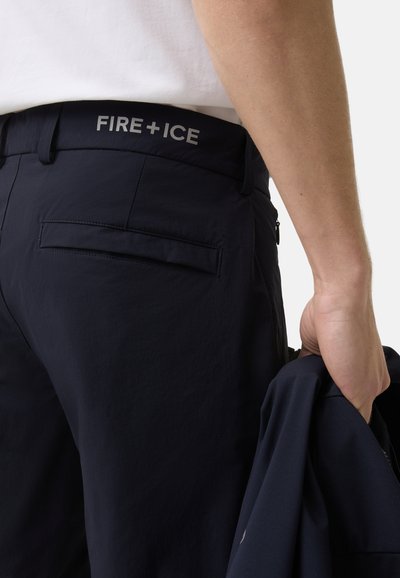 Marineblaue Hose mit glatter Textur, ausgestattet mit einer Gesäßtasche und einem Bund, der mit der kontrastierenden weißen Aufschrift "FIRE + ICE" versehen ist.