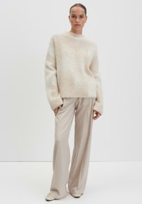Cream mohair sweater with a loose fit and wide sleeves, paired with beige wide-leg trousers and pointed toe shoes. Smooth, soft textures.