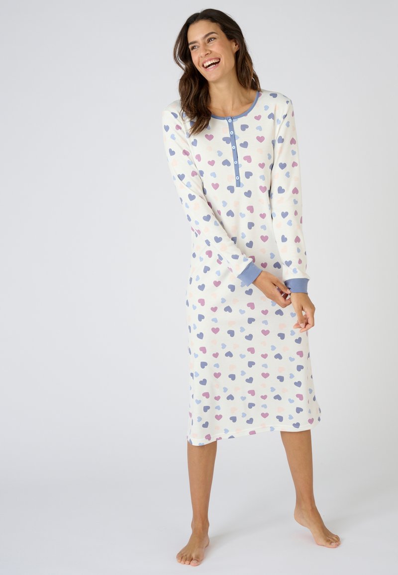 Camisa de noche de algodón con fondo crema y patrones de corazones en tonos pastel, con escote redondo y tapeta de botones, con mangas largas y corte a la altura de la rodilla.