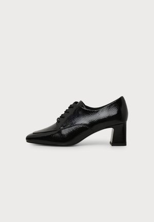 Chaussure noire en cuir verni à petit talon, avec lacets à l'avant et talon carré, vue de profil sur fond blanc.