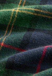 Uldent stof i grøn og marine ternet mønster, med røde og gule plaid detaljer. Blød tekstur med en let glans.