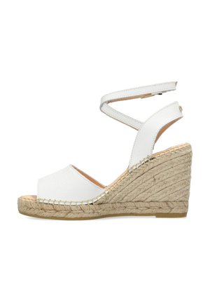Sandalo con zeppa in pelle bianca, con accento in juta intrecciata e cinturino alla caviglia. Design open toe con un tacco a zeppa testurizzato.