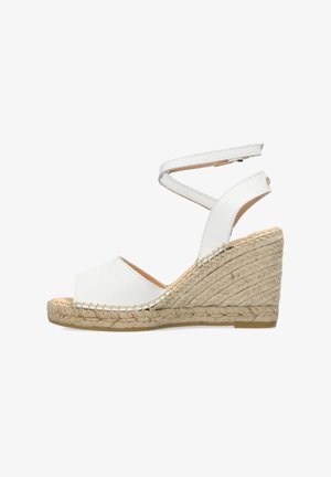 Sandale compensée blanche en cuir avec accent en jute tissé et bride de cheville. Design à bout ouvert avec un talon compensé texturé.