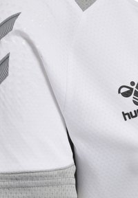 White sports jersey featuring a textured pattern, gray sleeve accents, and a black logo on the chest.