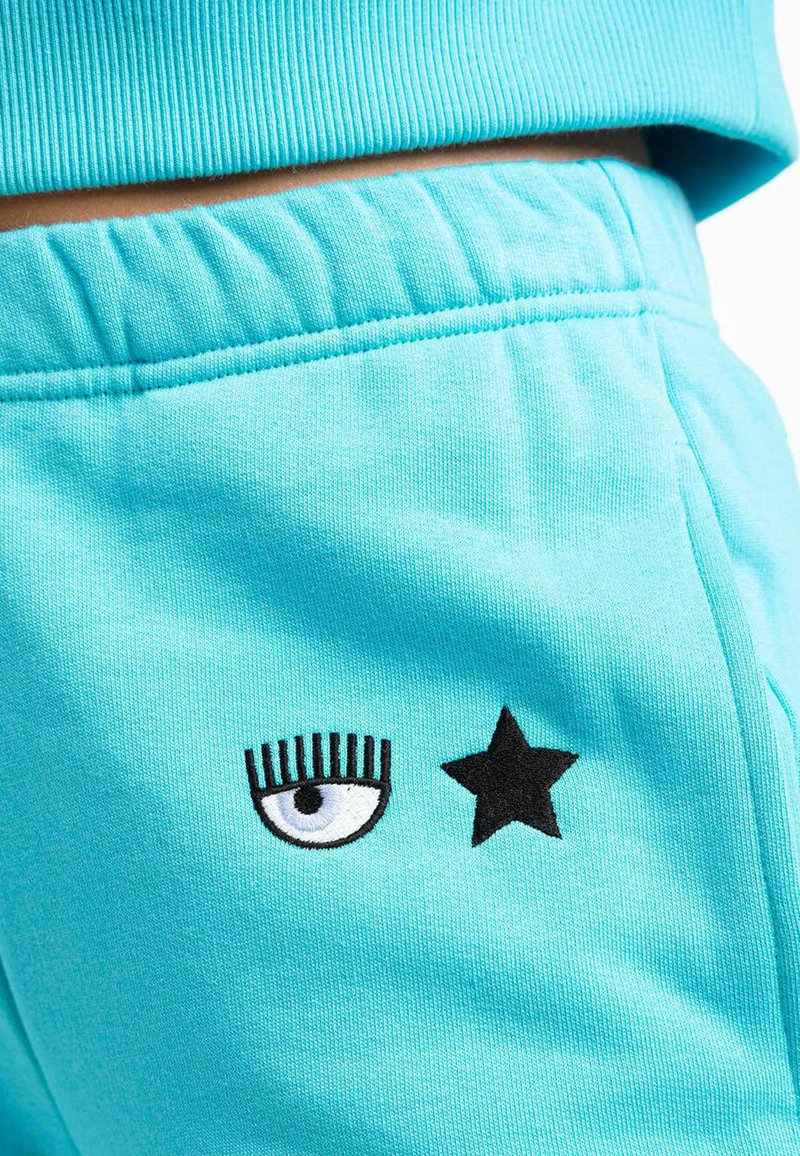 Türkisen Jogginghose mit schwarzem gesticktem Auge und Sternenmotiven. Weicher Stoff mit elastischem Bund für eine bequeme Passform.