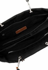 Intérieur d'un sac à main en tissu noir avec deux poches zippées, une étiquette en cuir et des accessoires en métal argenté. Doublure texturée et détails de couture sur les côtés.