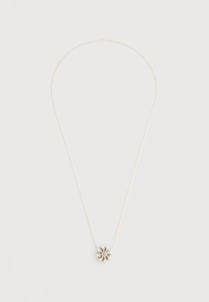 Collier délicat en perles d'argent avec un petit pendentif en forme de fleur finement conçu au centre sur un fond uni.