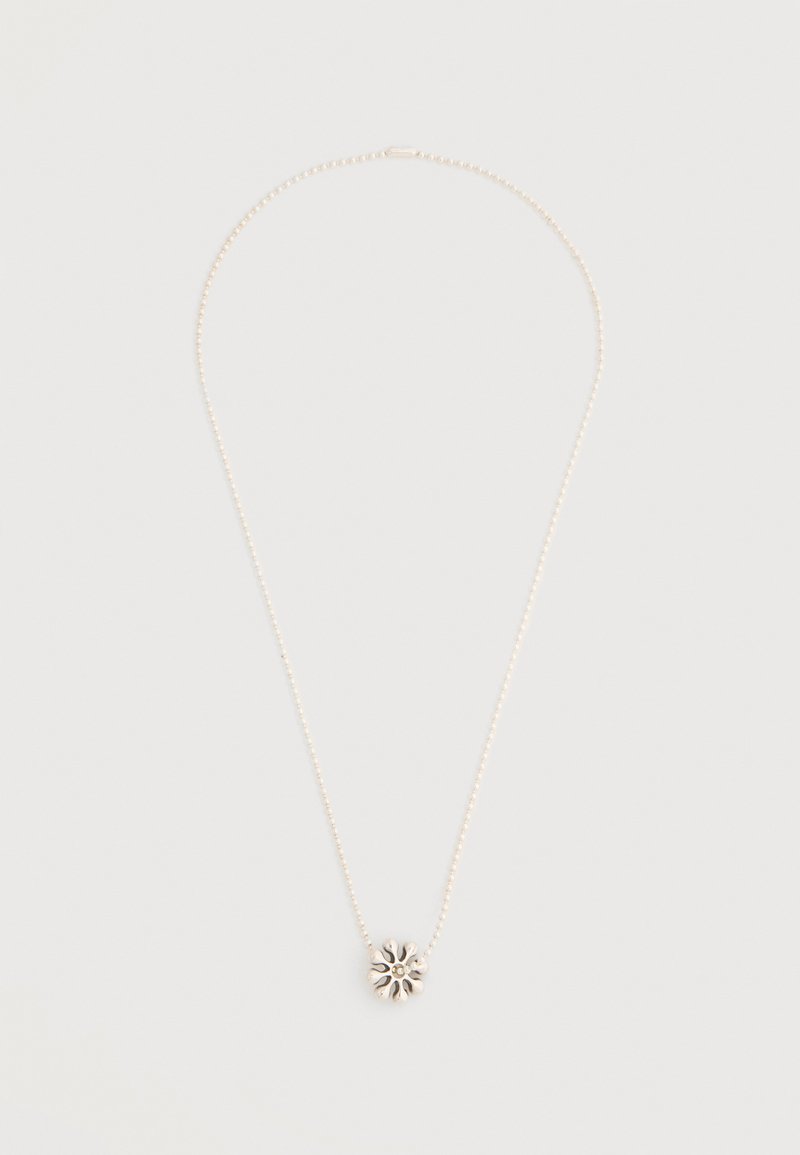 Λεπτό ασημένιο κολιέ με χάντρες και ένα μικρό, περίτεχνα σχεδιασμένο μενταγιόν σε σχήμα άνθης στο κέντρο, σε απλό φόντο.