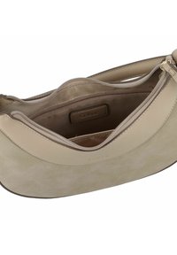 Bolso beige que presenta un exterior de cuero suave con un detalle de ante suave. El interior incluye un bolsillo con cremallera y una etiqueta con el logotipo de Gabor.