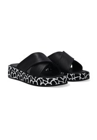 Sorte læder slide sandaler med krydsstraps og en mønstret hvid og sort platform med et giraffelignende print.